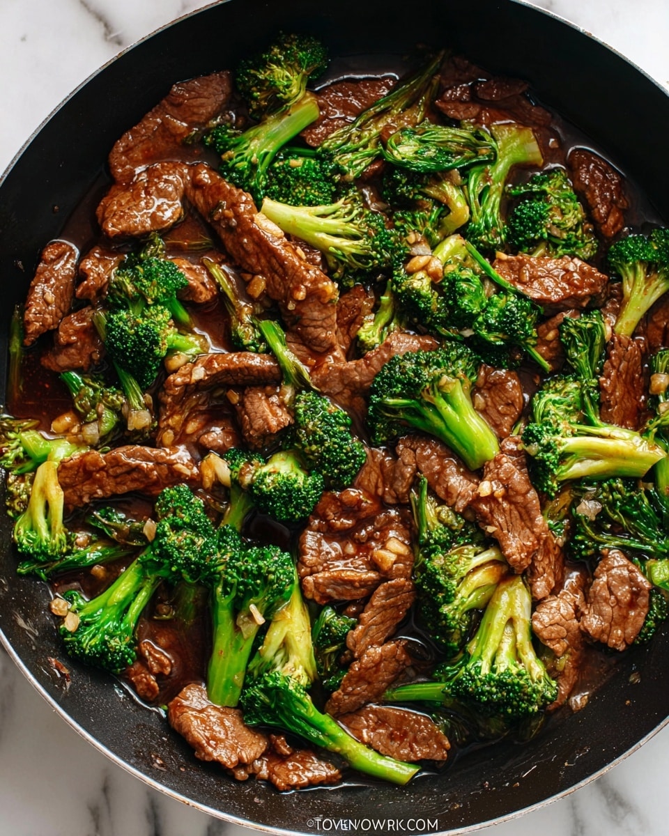 A close-up of a large black pan filled with stir-fried beef and broccoli. The dish has two main layers: tender, thin slices of brown cooked beef scattered throughout and bright green broccoli florets with lighter green stems mixed evenly in the pan. The beef and broccoli are coated in a shiny, thick brown sauce that pools slightly in the pan, adding a glossy texture. Small bits of garlic or ginger are visible on the meat and vegetables, adding texture. The pan sits on a white marbled surface. Photo taken with an iphone --ar 4:5 --v 7