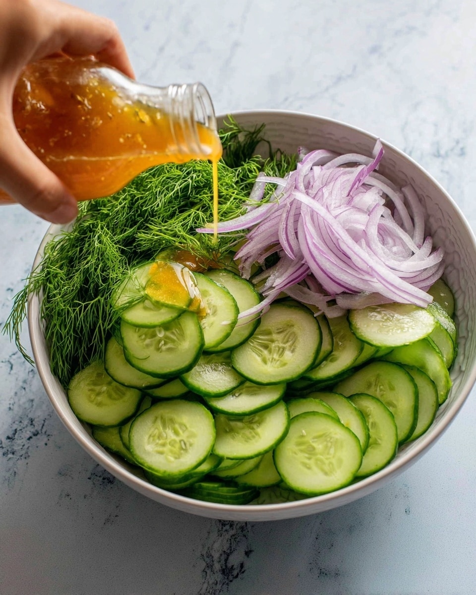 A white bowl sits on a white marbled surface filled with thinly sliced, round cucumber pieces layered at the bottom, showing a fresh green color and smooth texture. On the right side, thin strips of light purple onion are stacked in a small mound. To the left, there is a bunch of bright green dill adding a soft, feathery texture. A woman's hand is pouring a golden-orange dressing from a small glass bottle over the onions and cucumbers. The lighting is bright, highlighting the freshness and moisture of the vegetables. photo taken with an iphone --ar 4:5 --v 7