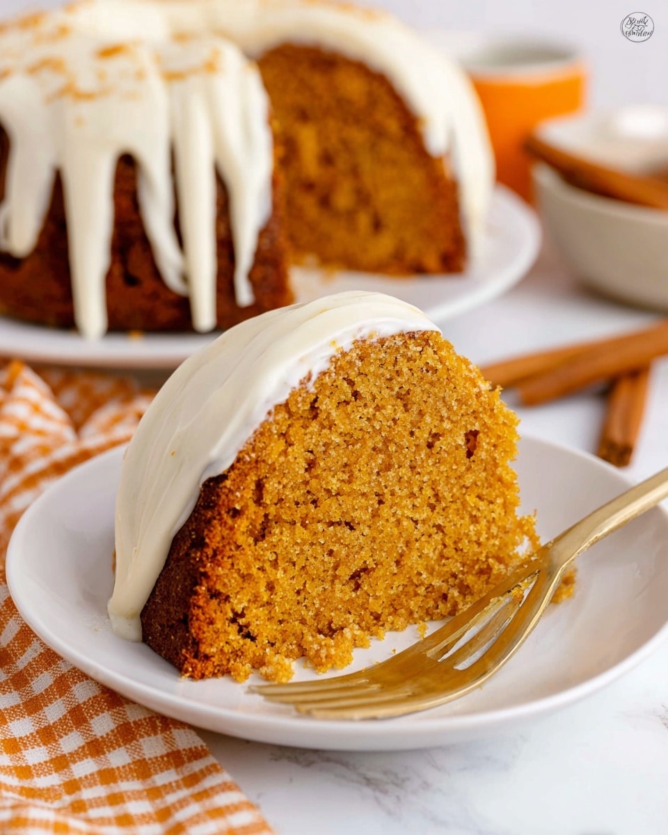 A close-up view of a single thick slice of orange-brown moist cake with a slightly crumbly texture on a white plate, showing one layer of the cake with a smooth creamy white frosting coating the bottom edge and part of the side, a gold fork placed next to the cake on the plate. In the background, a white plate with the whole cake covered in white frosting drizzle is visible, sitting on a white marbled surface with a cinnamon stick and an orange-and-white checkered cloth nearby. Photo taken with an iphone --ar 4:5 --v 7